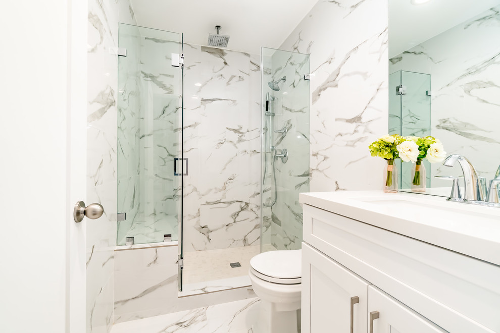 This is an example of a small contemporary 3/4 bathroom in Salt Lake City with shaker cabinets, white cabinets, an alcove shower, a one-piece toilet, white tile, marble, white walls, marble floors, an undermount sink, solid surface benchtops, white floor, a hinged shower door and white benchtops.