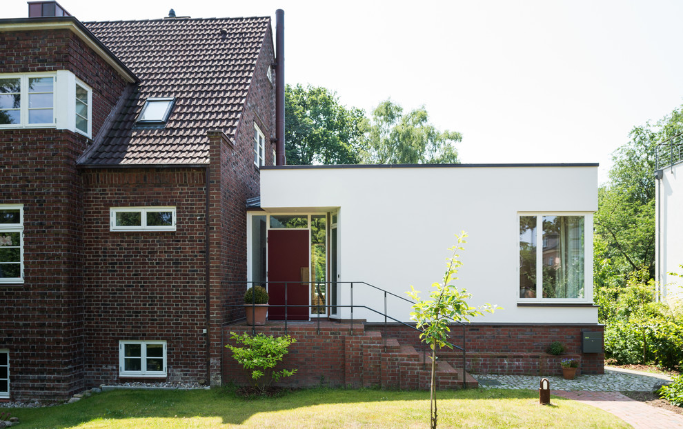 This is an example of a contemporary split-level brick white exterior in Hamburg with a flat roof.