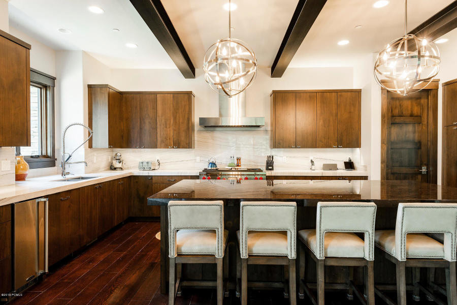Inspiration for a large contemporary l-shaped open plan kitchen in Salt Lake City with an undermount sink, flat-panel cabinets, dark wood cabinets, quartzite benchtops, white splashback, stone slab splashback, stainless steel appliances, dark hardwood floors, with island, brown floor and white benchtop.