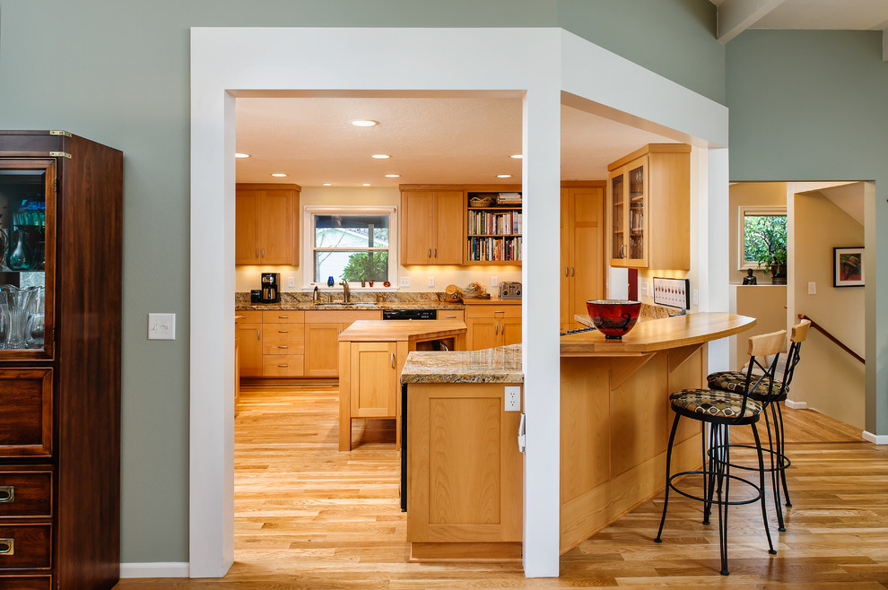 This is an example of a traditional u-shaped kitchen in Other with shaker cabinets, medium wood cabinets, medium hardwood floors and with island.