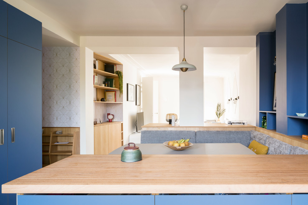Mid-sized contemporary single-wall open plan kitchen in Paris with a single-bowl sink, flat-panel cabinets, blue cabinets, wood benchtops, metallic splashback, timber splashback, coloured appliances, ceramic floors, with island, turquoise floor and beige benchtop.