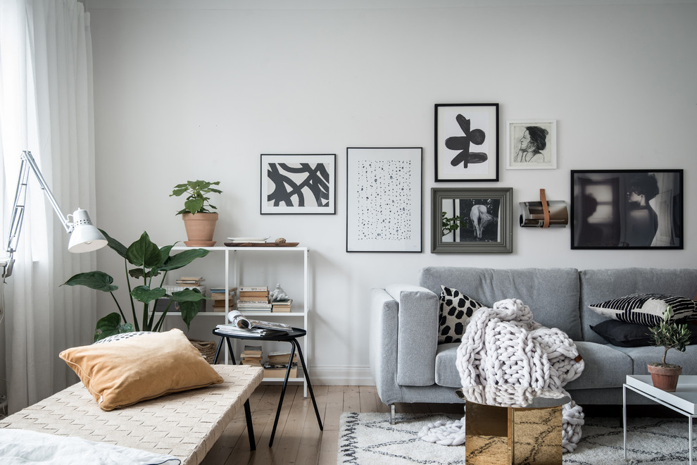 Design ideas for a mid-sized scandinavian enclosed living room in Gothenburg with white walls, light hardwood floors, no fireplace and beige floor.
