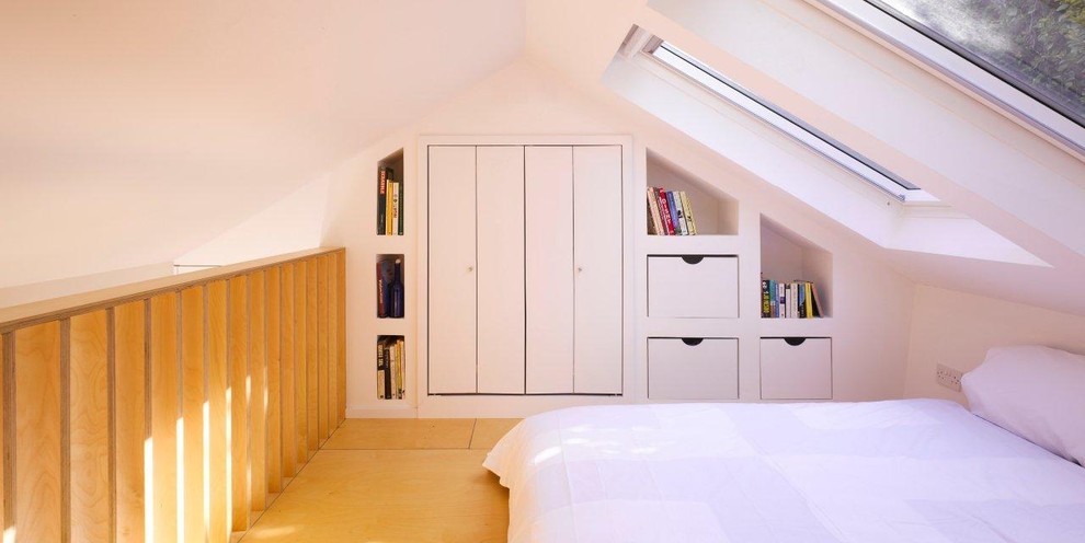 Contemporary loft-style bedroom in Dublin with white walls and plywood floors.