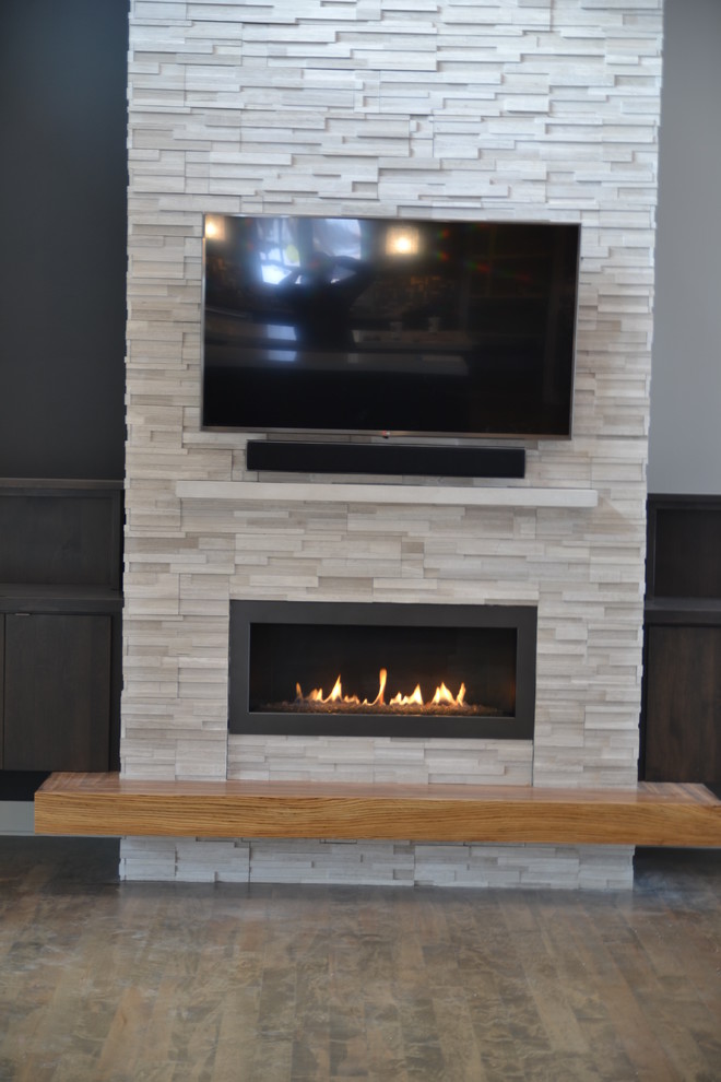 Photo of a mid-sized contemporary open concept family room in Milwaukee with a ribbon fireplace, a stone fireplace surround, a wall-mounted tv, grey walls, medium hardwood floors and brown floor.