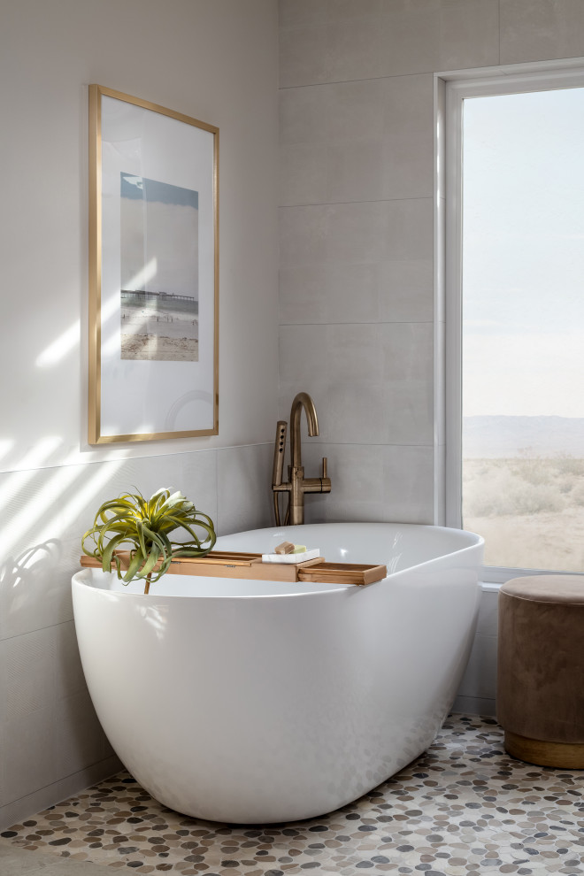 Immagine di una stanza da bagno padronale minimalista con ante lisce, vasca freestanding, piastrelle bianche, pavimento con piastrelle di ciottoli e piastrelle in ceramica