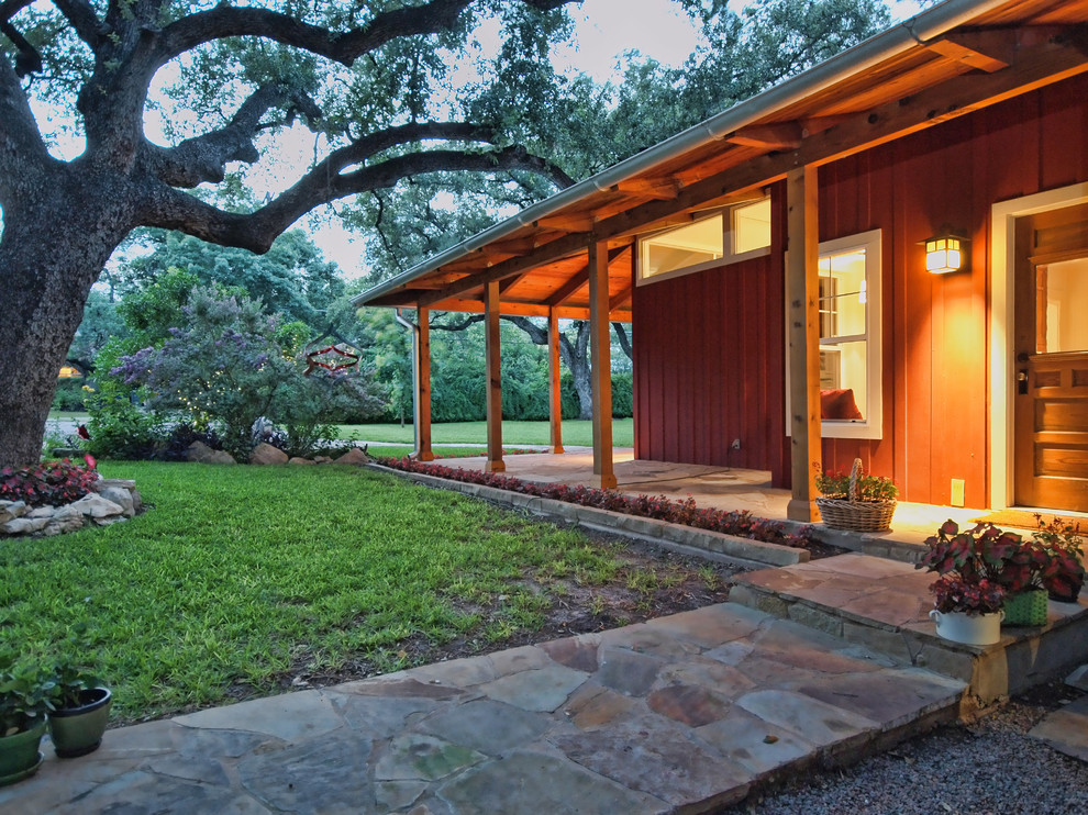 Photo of a mid-sized country verandah in Austin with natural stone pavers.