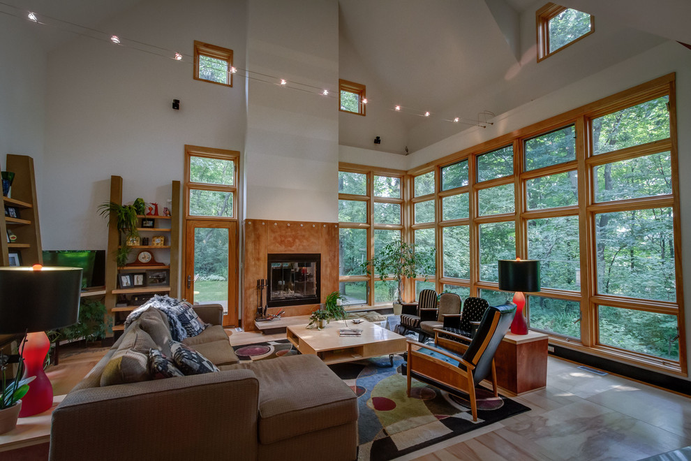 Photo of a large contemporary open concept living room in Minneapolis with plywood floors, a standard fireplace and a concrete fireplace surround.