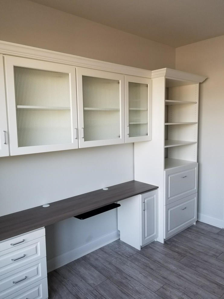 This is an example of a mid-sized transitional home office in Charleston with grey walls, medium hardwood floors, a built-in desk and grey floor.