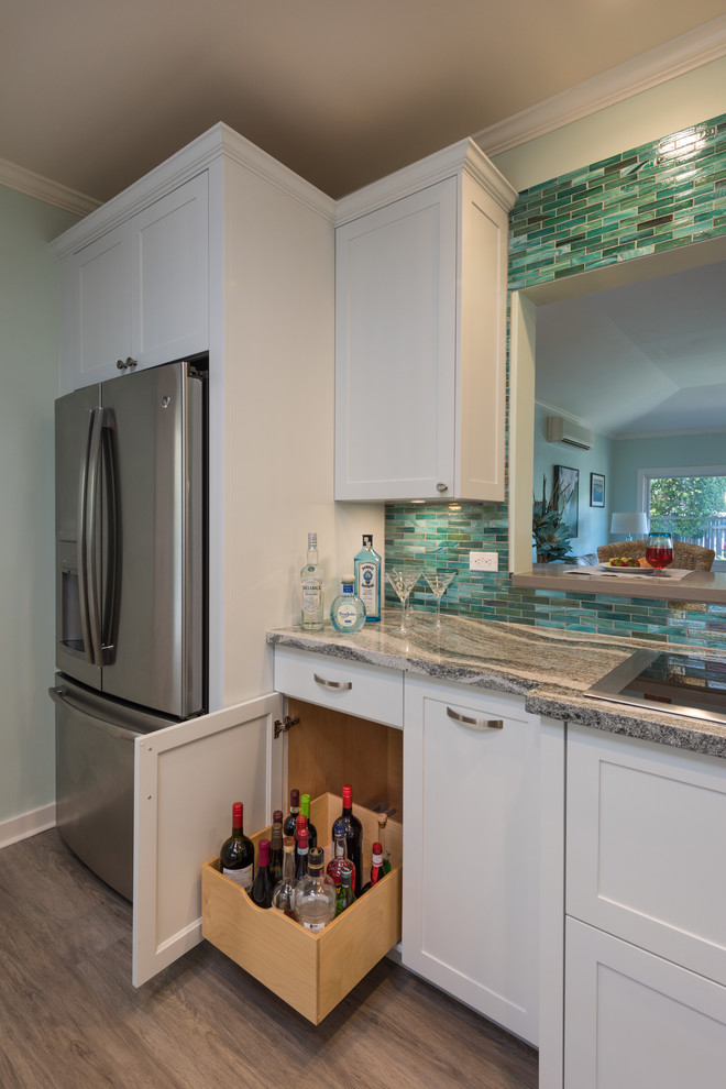 This is an example of a mid-sized tropical separate kitchen in Hawaii with an undermount sink, shaker cabinets, white cabinets, quartzite benchtops, blue splashback, glass tile splashback, panelled appliances, vinyl floors, no island and grey floor.