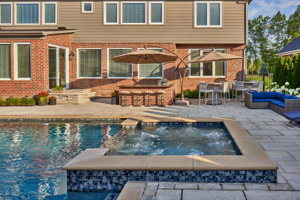 Cette photo montre une grande piscine arrière tendance rectangle avec un bain bouillonnant et des pavés en béton.