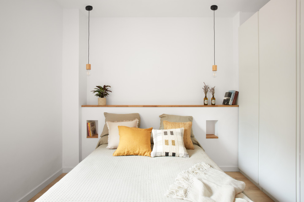Ejemplo de dormitorio principal y blanco y madera escandinavo pequeño con paredes blancas, suelo laminado y suelo marrón