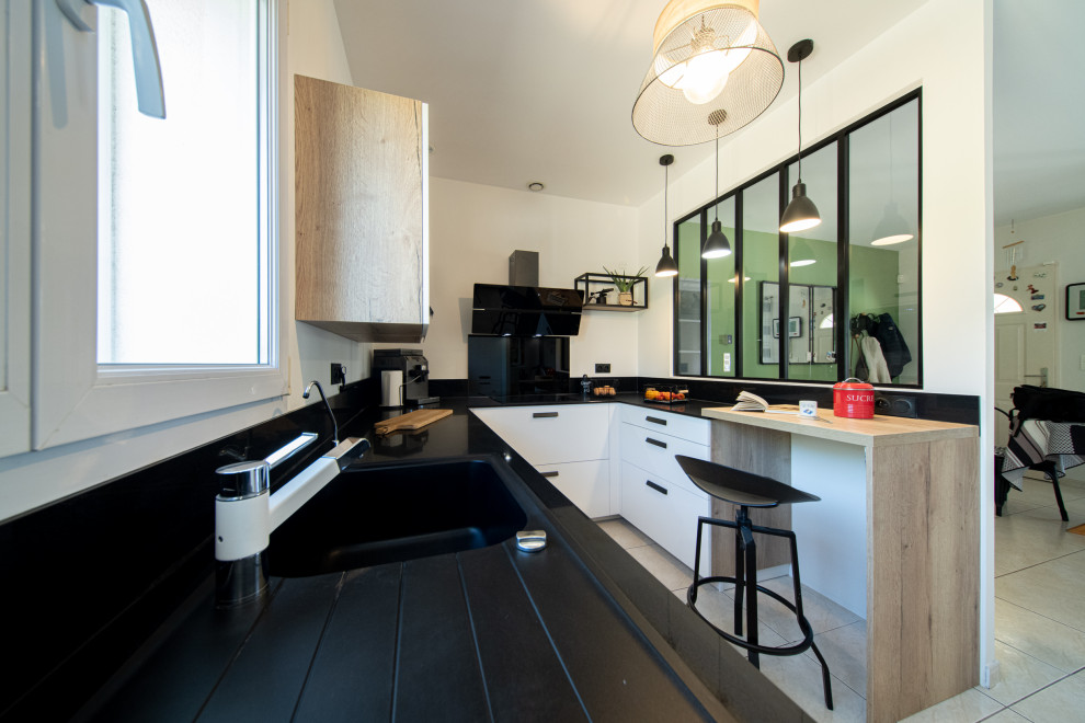 Exemple d'une petite cuisine blanche et bois industrielle avec un évier 1 bac, une crédence noire, un électroménager noir, plan de travail noir et fenêtre au-dessus de l'évier.