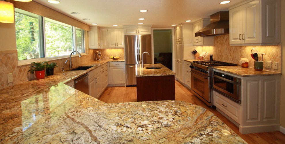 Eat-in kitchen - large transitional u-shaped medium tone wood floor eat-in kitchen idea in Denver with an undermount sink, raised-panel cabinets, white cabinets, granite countertops, beige backsplash, ceramic backsplash, stainless steel appliances and an island