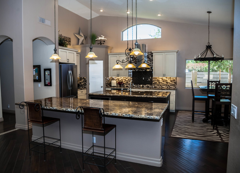 Inspiration for a large transitional l-shaped dark wood floor eat-in kitchen remodel in Phoenix with an undermount sink, recessed-panel cabinets, white cabinets, granite countertops, multicolored backsplash, glass tile backsplash, stainless steel appliances and an island