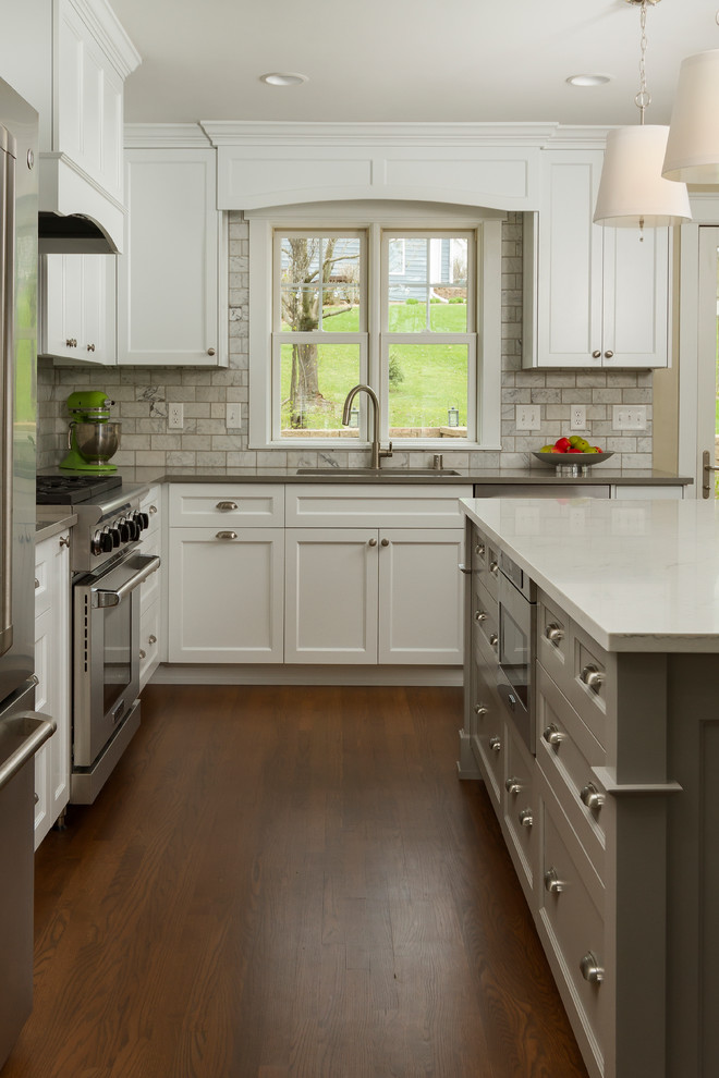 Inspiration for a mid-sized transitional l-shaped eat-in kitchen in Minneapolis with an undermount sink, shaker cabinets, white cabinets, quartzite benchtops, white splashback, marble splashback, stainless steel appliances, medium hardwood floors, with island and brown floor.