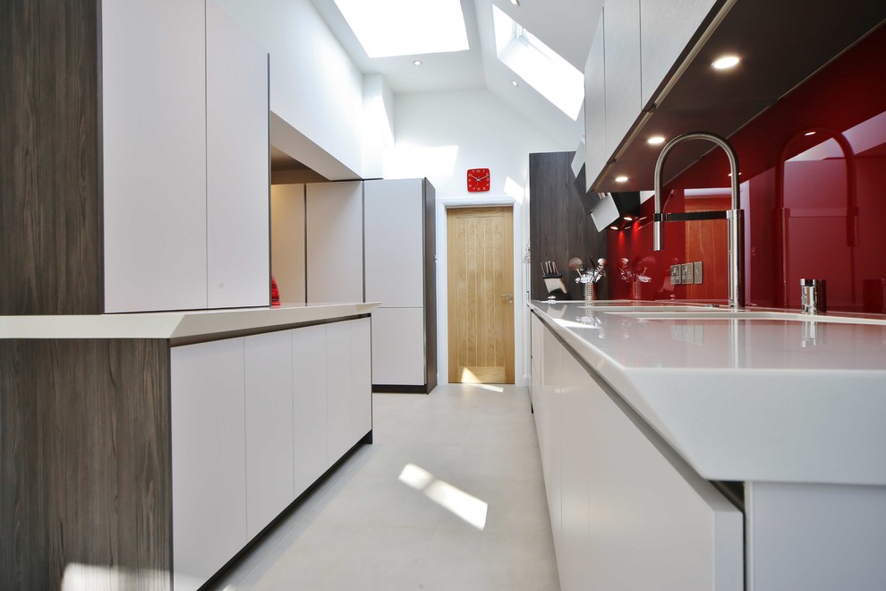 Design ideas for a large contemporary galley open plan kitchen in London with flat-panel cabinets, medium wood cabinets, quartzite benchtops, red splashback, glass sheet splashback, stainless steel appliances and a peninsula.