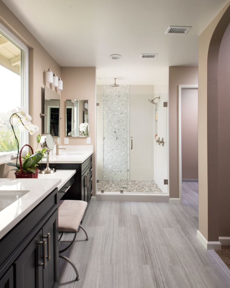 Photo of a mid-sized transitional master bathroom in San Diego with shaker cabinets, black cabinets, an alcove shower, a one-piece toilet, multi-coloured tile, glass tile, beige walls, light hardwood floors, an integrated sink and marble benchtops.