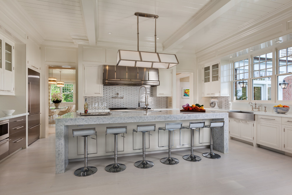 Inspiration for a transitional kitchen in New York with recessed-panel cabinets, white cabinets, metallic splashback, stainless steel appliances, light hardwood floors and with island.