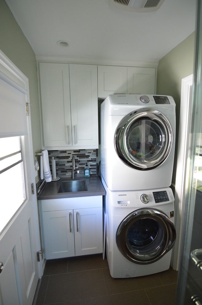 Small transitional single-wall utility room in Los Angeles with a single-bowl sink, white cabinets, green walls and a stacked washer and dryer.