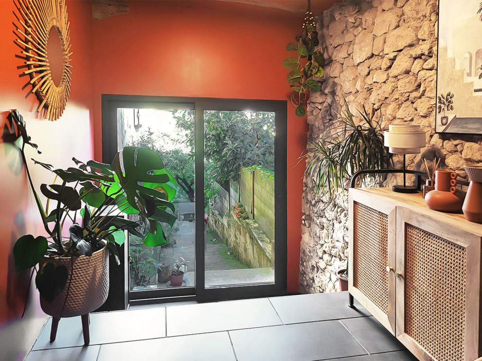 Design ideas for a small tropical foyer with orange walls, ceramic floors, a single front door, a black front door, black floor and exposed beam.