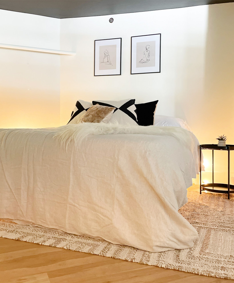 На фото: двухуровневая гостиная комната в стиле лофт с белыми стенами, светлым паркетным полом, отдельно стоящим телевизором и балками на потолке с