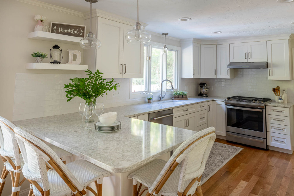 Mid-sized transitional u-shaped medium tone wood floor and brown floor kitchen photo in Boston with an undermount sink, shaker cabinets, white cabinets, quartz countertops, white backsplash, ceramic backsplash, stainless steel appliances, a peninsula and gray countertops