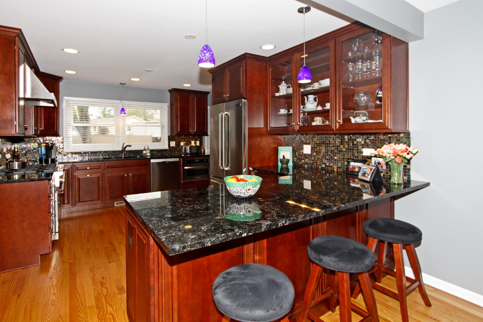 Example of a mid-sized transitional u-shaped light wood floor eat-in kitchen design in Chicago with an undermount sink, raised-panel cabinets, medium tone wood cabinets, granite countertops, multicolored backsplash, glass tile backsplash, stainless steel appliances and a peninsula