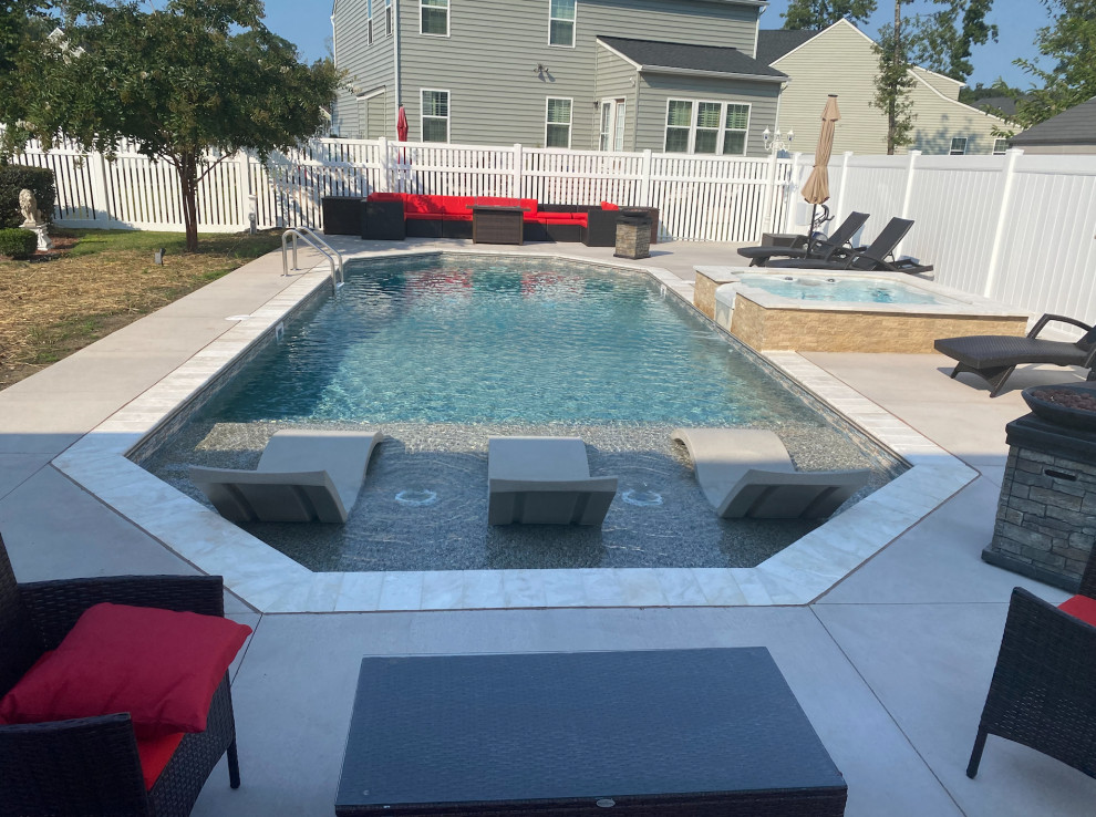 Esempio di una piscina naturale contemporanea personalizzata di medie dimensioni e dietro casa con una vasca idromassaggio e lastre di cemento