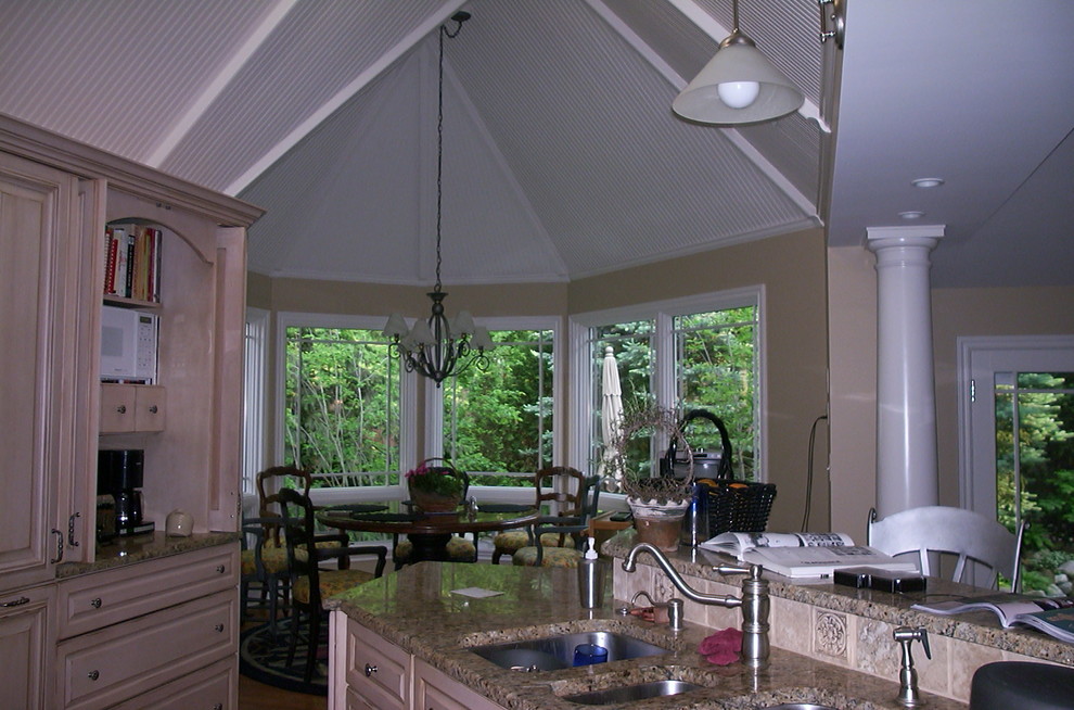 Elegant u-shaped eat-in kitchen photo with a triple-bowl sink, raised-panel cabinets, light wood cabinets, granite countertops, beige backsplash and mosaic tile backsplash