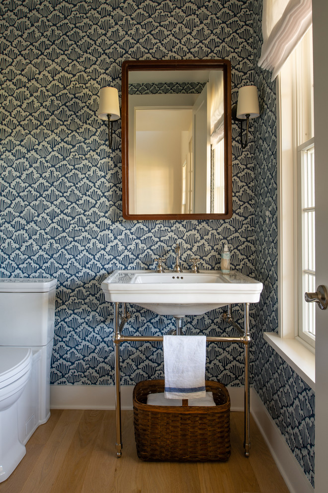 Photo of a mid-sized country powder room in DC Metro with blue walls, medium hardwood floors, a console sink and brown floor.
