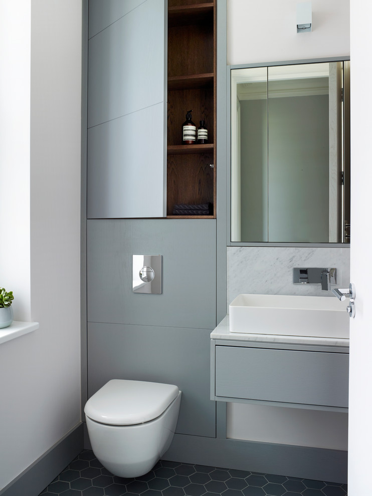 Contemporary bathroom in London with flat-panel cabinets, grey cabinets, a wall-mount toilet, white walls, mosaic tile floors, a vessel sink, grey floor and white benchtops.