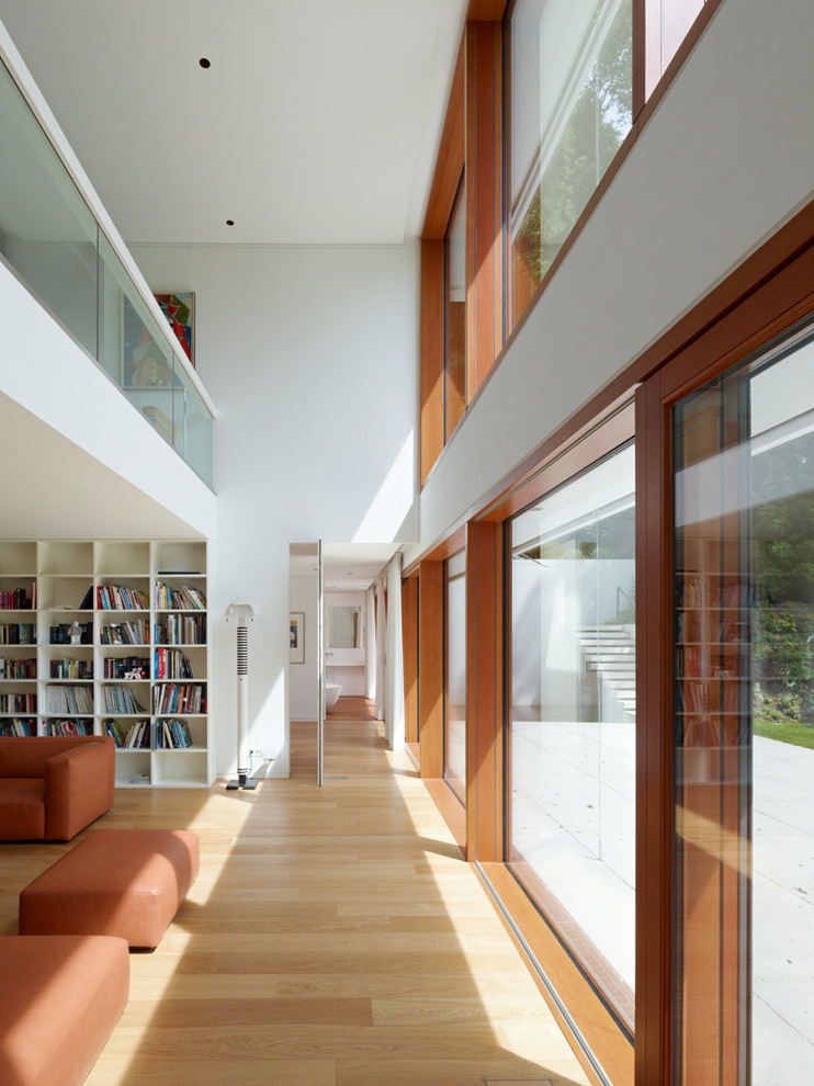 Large contemporary living room in Stuttgart with a library, white walls and light hardwood floors.