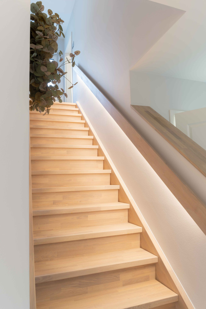 Foto de escalera recta minimalista con escalones de madera, contrahuellas de madera y barandilla de madera