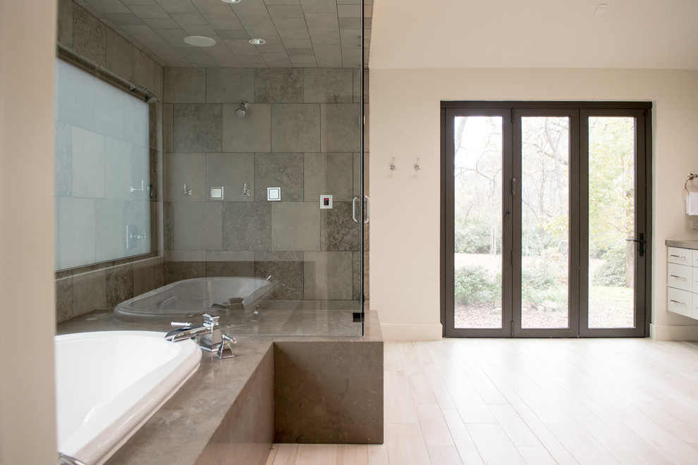 Example of a mid-sized transitional master gray tile and cement tile light wood floor and beige floor drop-in bathtub design in Dallas with flat-panel cabinets, gray cabinets, gray walls, a drop-in sink, concrete countertops and a hinged shower door