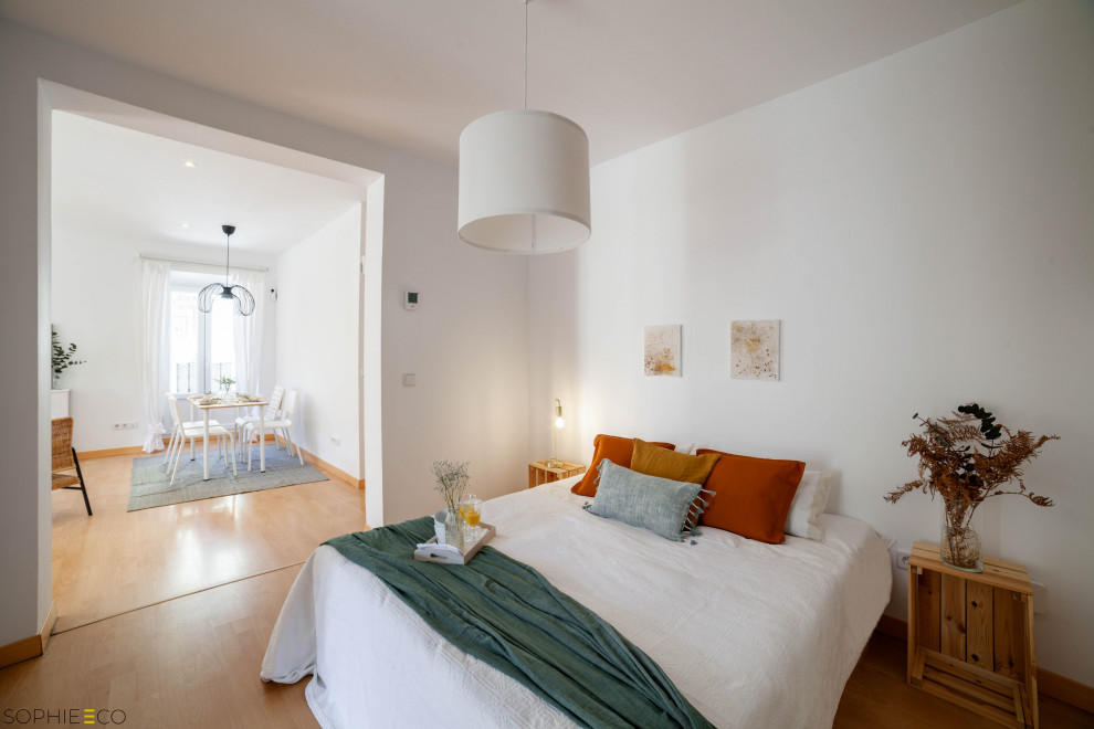 Modelo de dormitorio tipo loft y blanco y madera ecléctico grande con paredes blancas, suelo laminado y suelo marrón