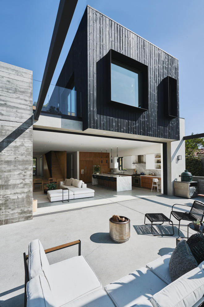This is an example of a medium sized and black contemporary two floor detached house in Los Angeles with wood cladding, a flat roof and a mixed material roof.