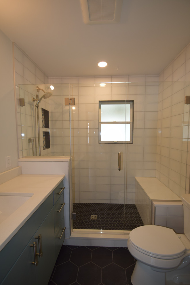 Example of a transitional 3/4 white tile and ceramic tile ceramic tile, gray floor and single-sink alcove shower design with shaker cabinets, blue cabinets, a one-piece toilet, multicolored walls, an undermount sink, quartz countertops, a hinged shower door, white countertops, a niche and a built-in vanity