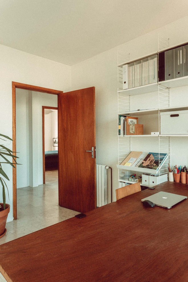 Foto på ett litet eklektiskt hemmabibliotek, med vita väggar, marmorgolv, ett fristående skrivbord och grått golv