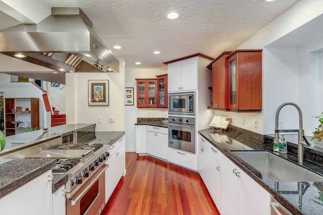 Inspiration for a mid-sized modern galley dark wood floor and multicolored floor eat-in kitchen remodel in Portland with a single-bowl sink, flat-panel cabinets, white cabinets, granite countertops, black backsplash, stone slab backsplash, stainless steel appliances and black countertops