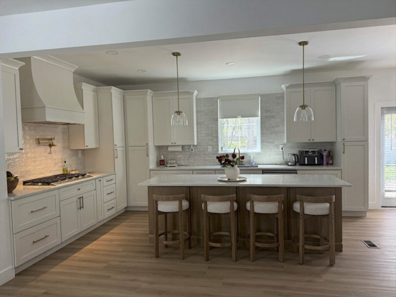 Example of a large minimalist l-shaped vinyl floor and brown floor eat-in kitchen design in Baltimore with shaker cabinets, white cabinets, solid surface countertops, white backsplash, stone tile backsplash, stainless steel appliances, an island and orange countertops