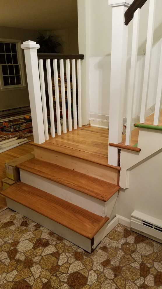 Large traditional wood l-shaped staircase in New York with wood risers and wood railing.