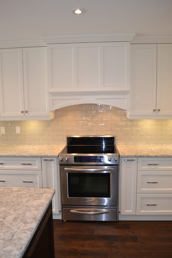 Inspiration for a mid-sized transitional single-wall dark wood floor open concept kitchen remodel in Toronto with a double-bowl sink, recessed-panel cabinets, white cabinets, quartz countertops, gray backsplash, porcelain backsplash, stainless steel appliances and an island
