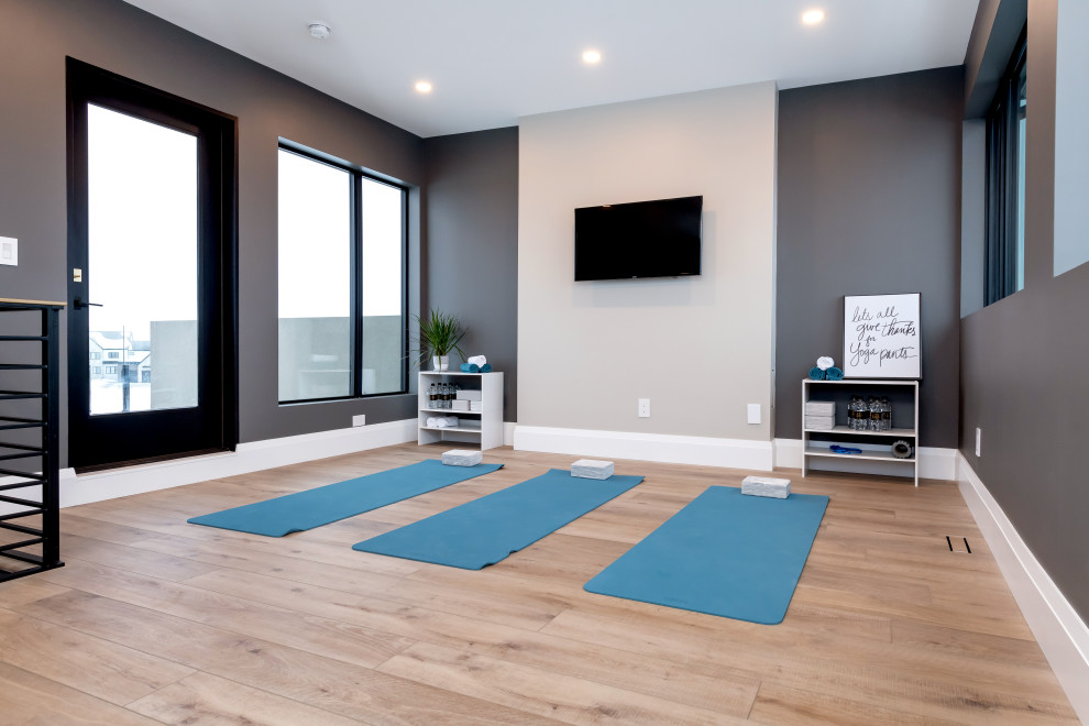 Exemple d'un très grand studio de yoga tendance avec un mur gris, un sol en bois brun et un sol marron.