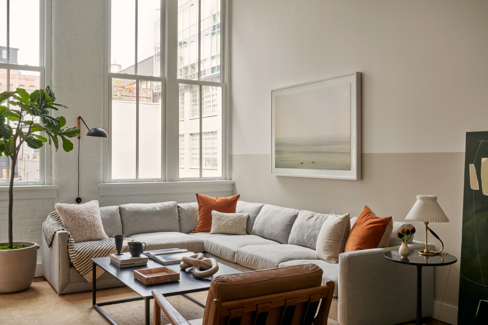 Mittelgroßes Modernes Wohnzimmer ohne Kamin, im Loft-Stil mit beiger Wandfarbe, braunem Holzboden, TV-Wand, braunem Boden, freigelegten Dachbalken und Ziegelwänden in New York