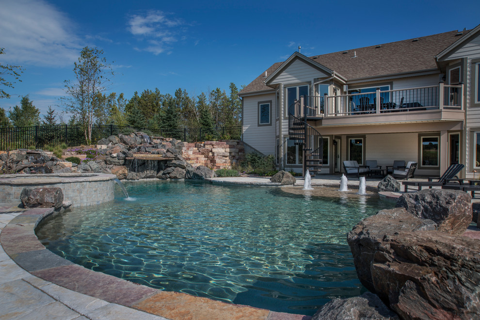 Mid-sized country backyard custom-shaped natural pool in Milwaukee with a hot tub and concrete pavers.