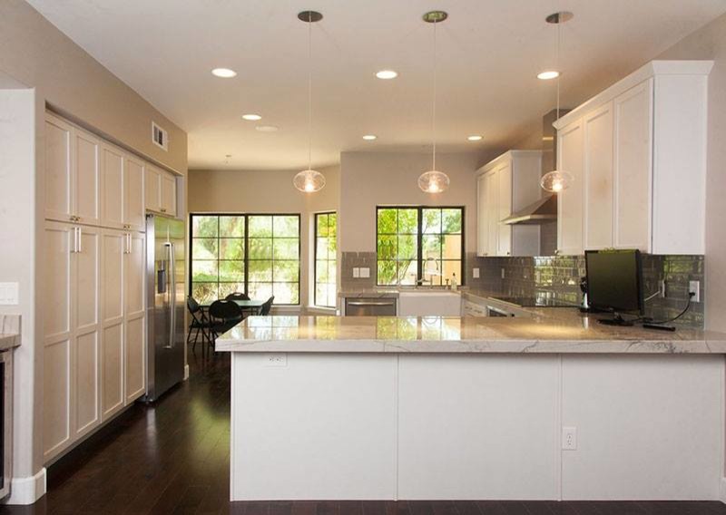 Example of a large transitional l-shaped slate floor kitchen design in Phoenix with shaker cabinets, white cabinets, quartz countertops, beige backsplash, subway tile backsplash and an island