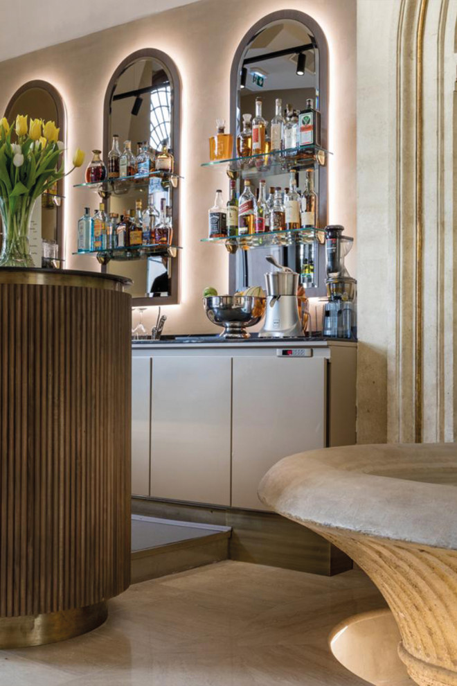 Expansive modern single-wall home bar in Los Angeles with flat-panel cabinets, beige cabinets, solid surface benchtops, beige splashback, ceramic splashback, plywood floors, beige floor and black benchtop.