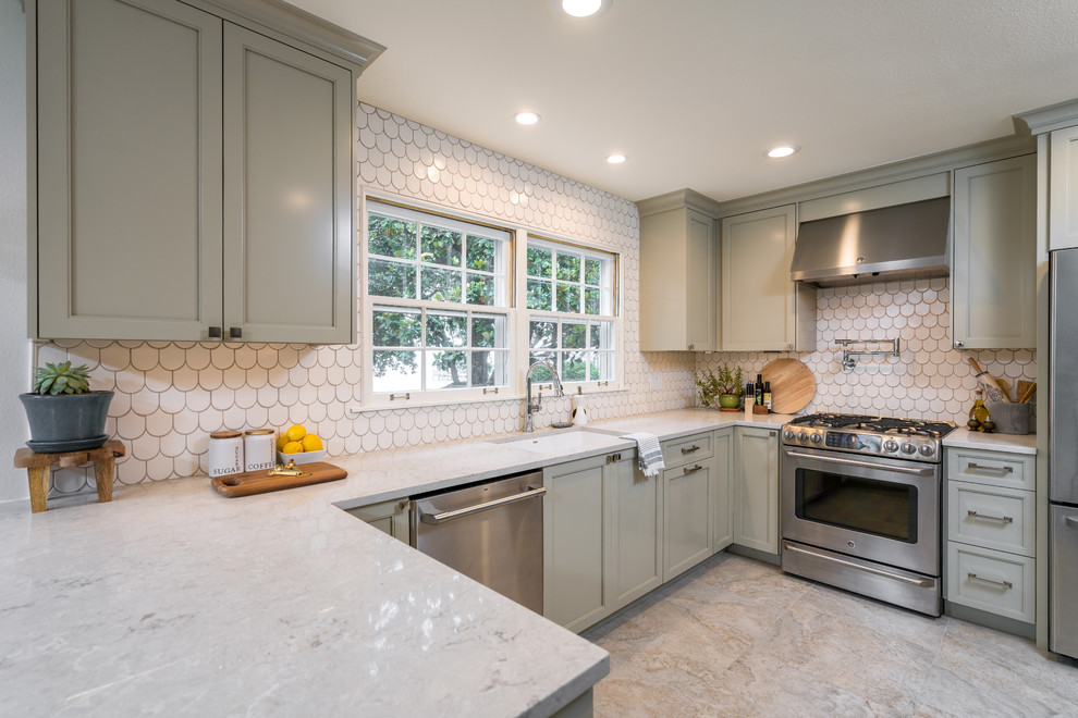 Inspiration for a large transitional u-shaped porcelain tile enclosed kitchen remodel with an undermount sink, shaker cabinets, gray cabinets, quartz countertops, white backsplash, ceramic backsplash, stainless steel appliances and a peninsula