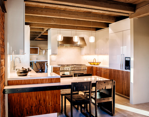 Modern kitchen cabinet design with warm wood base units, white glossy uppers, and stainless-steel appliances in an open-plan kitchen.