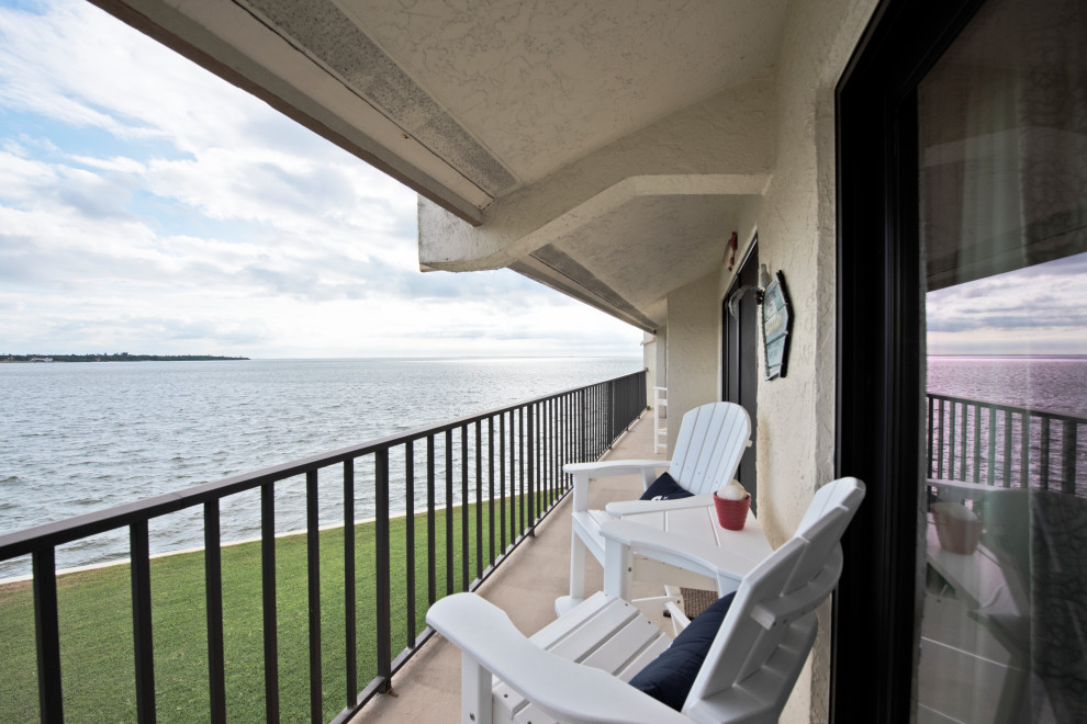 Cette photo montre un petit balcon bord de mer d'appartement avec une extension de toiture et un garde-corps en métal.